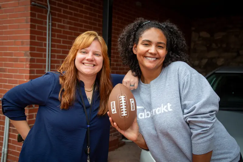 Two Abstrakt team members laughing with a football at the Touchdown team event