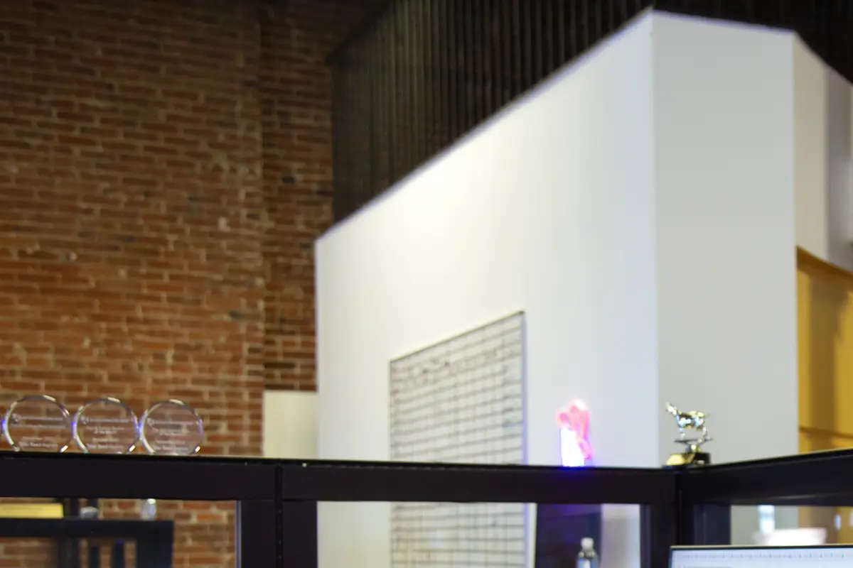 The Abstrakt sales floor in St. Louis: cubicles under exposed brick, with glass awards along the partition