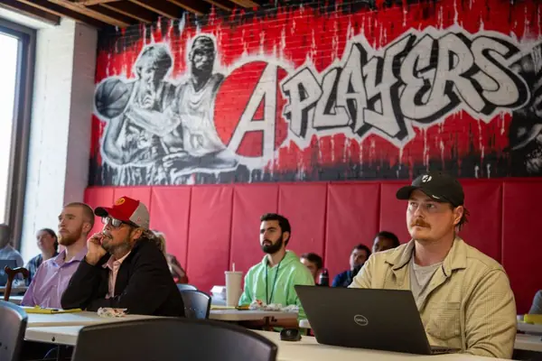 Abstrakt sales development reps at their desks under the A Players mural on the St. Louis campus
