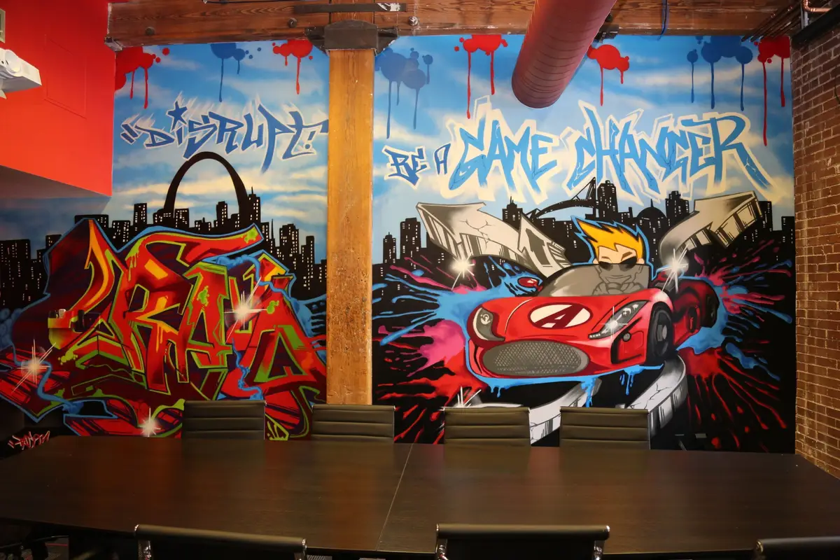 A conference room wrapped in graffiti murals, including the Gateway Arch and a Game Changer slogan