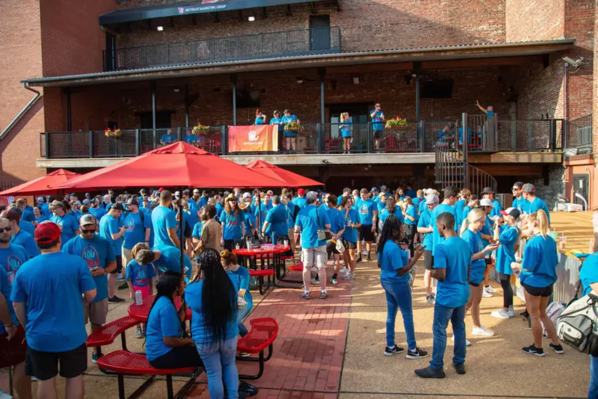 Volunteers in blue Give Back Day shirts gathering in a courtyard before heading out, 2022