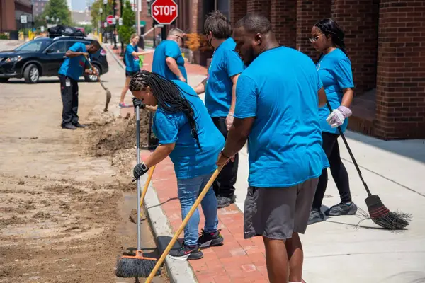 Volunteers sweeping dirt off a downtown sidewalk, 2022