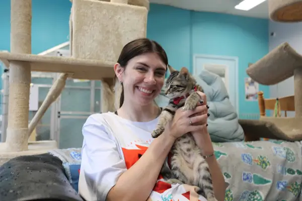 A volunteer holding a kitten at an animal shelter, 2023