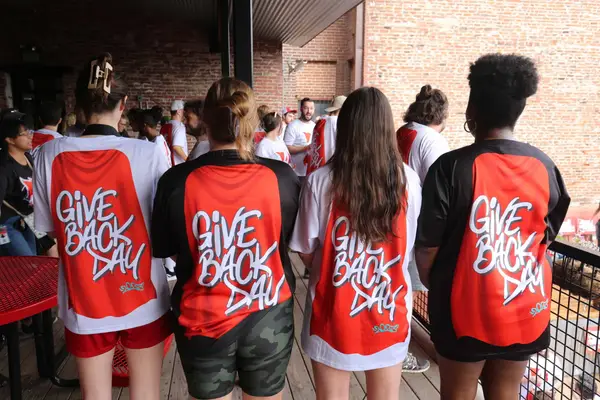 Volunteers showing the backs of their red Give Back Day jerseys, 2023