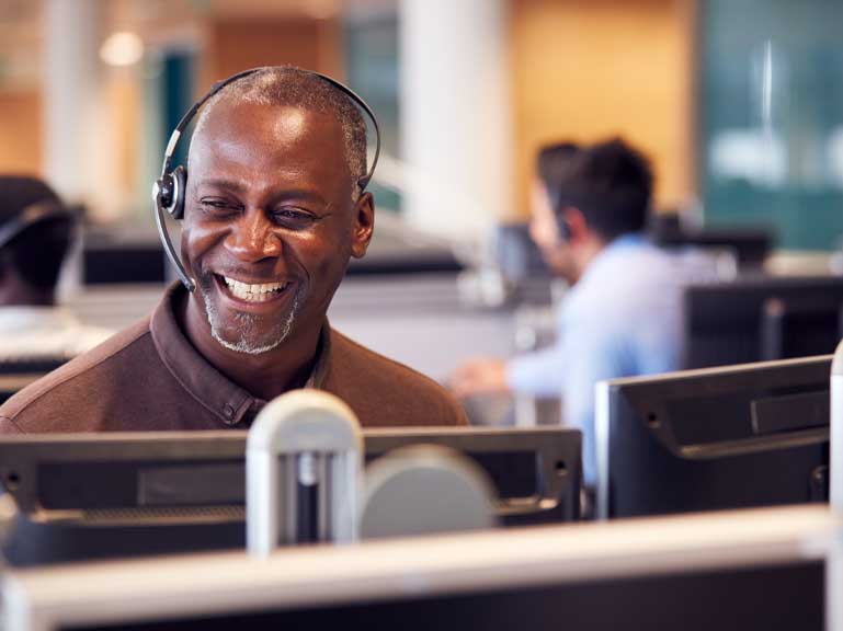 Man in a call center on the phone with a smile on his face