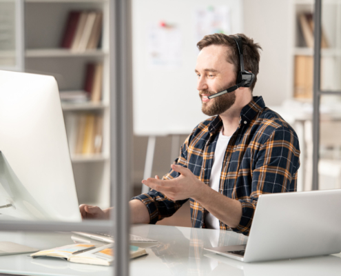 Man with a headset on talking in front of an imac