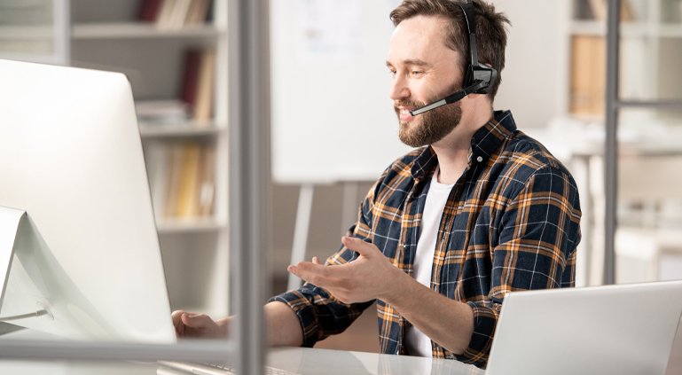 Man with a headset on talking in front of an imac