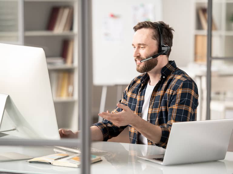 Man with a headset on talking in front of an imac