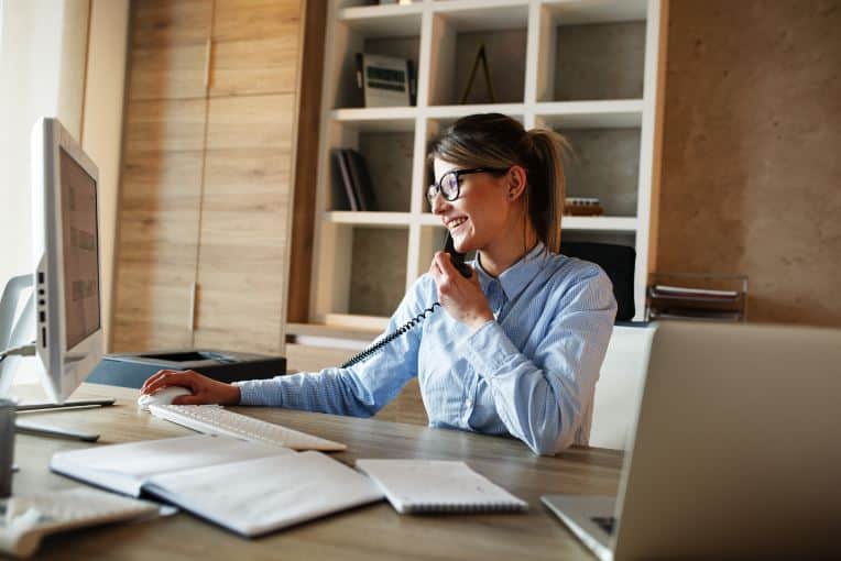 happy businesswoman sitting at her desk talking on the phone