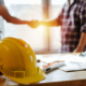 handshake deal at a construction site with a construction worker's hard hat