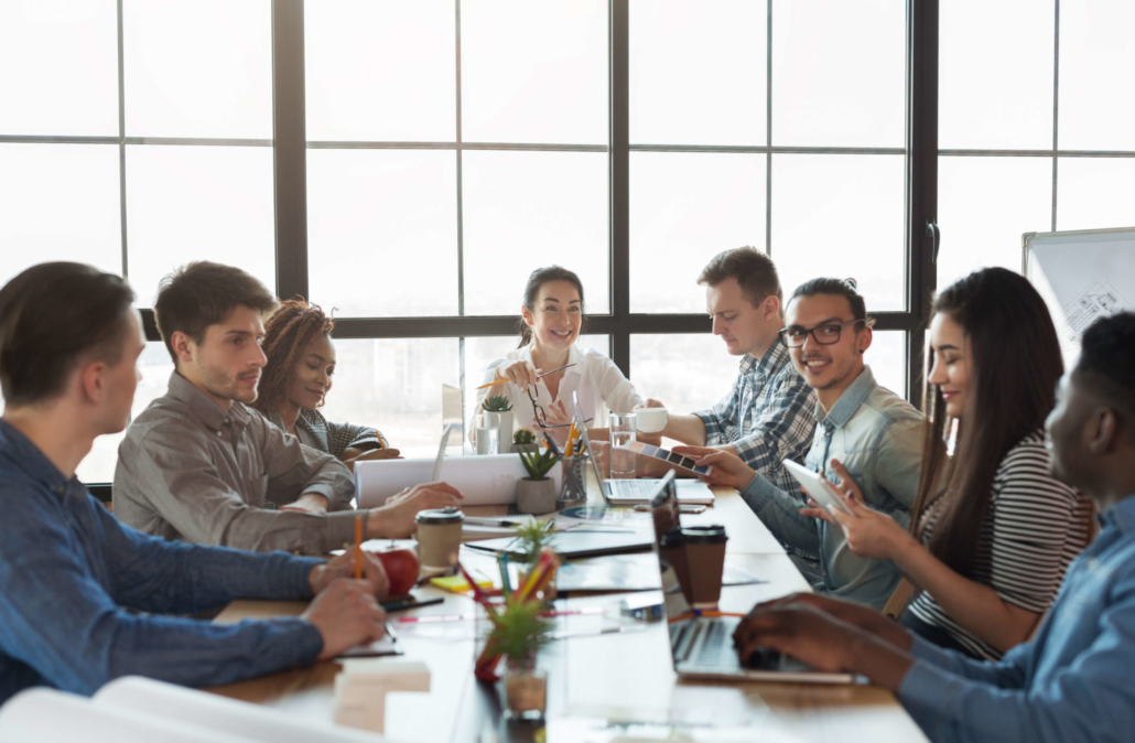 Sales Enablement Team sales team sitting at a table in a conference room talking and laughing