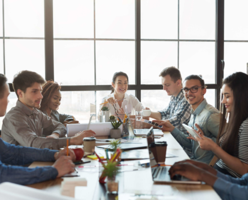 sales team sitting at a table in a conference room talking and laughing