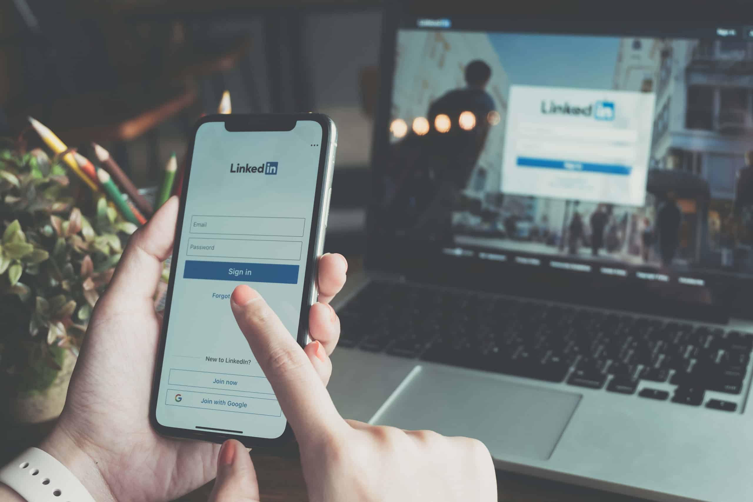 Professional marketer using LinkedIn on their iPhone and laptop