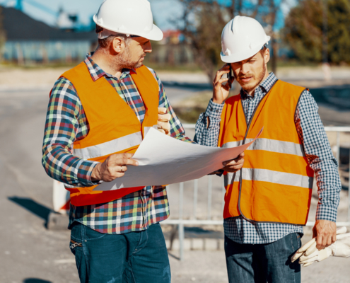 two paving construction workers talking about project plans