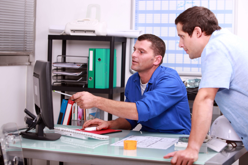 B2B Data Cleansing For Construction Companies two construction company employees in an office talking about what is on a computer screen