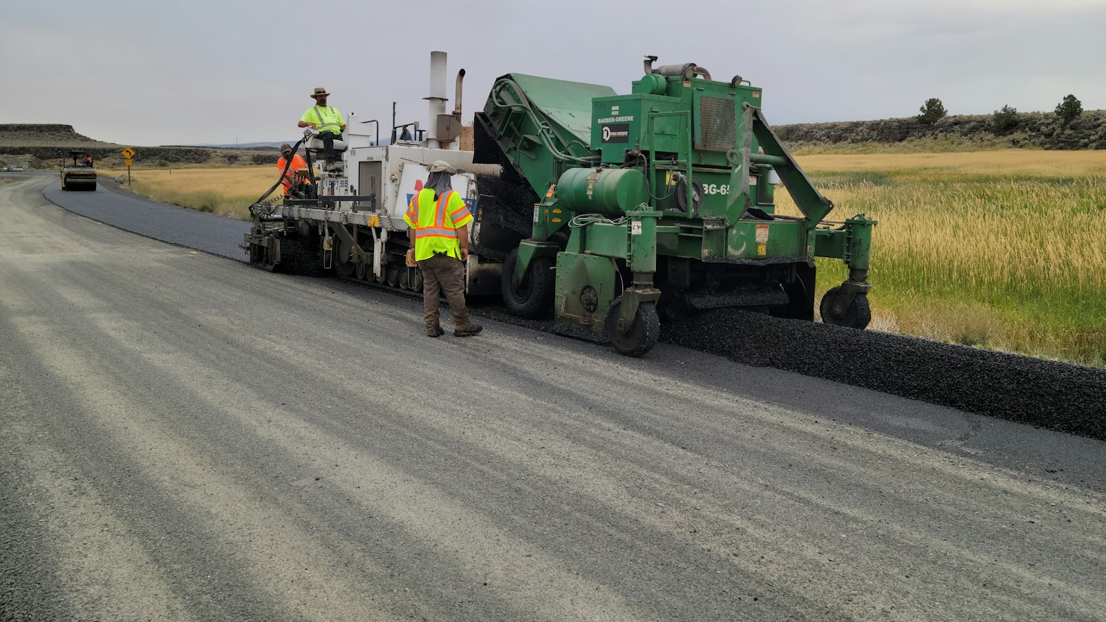 Paving crew and equipment laying fresh asphalt