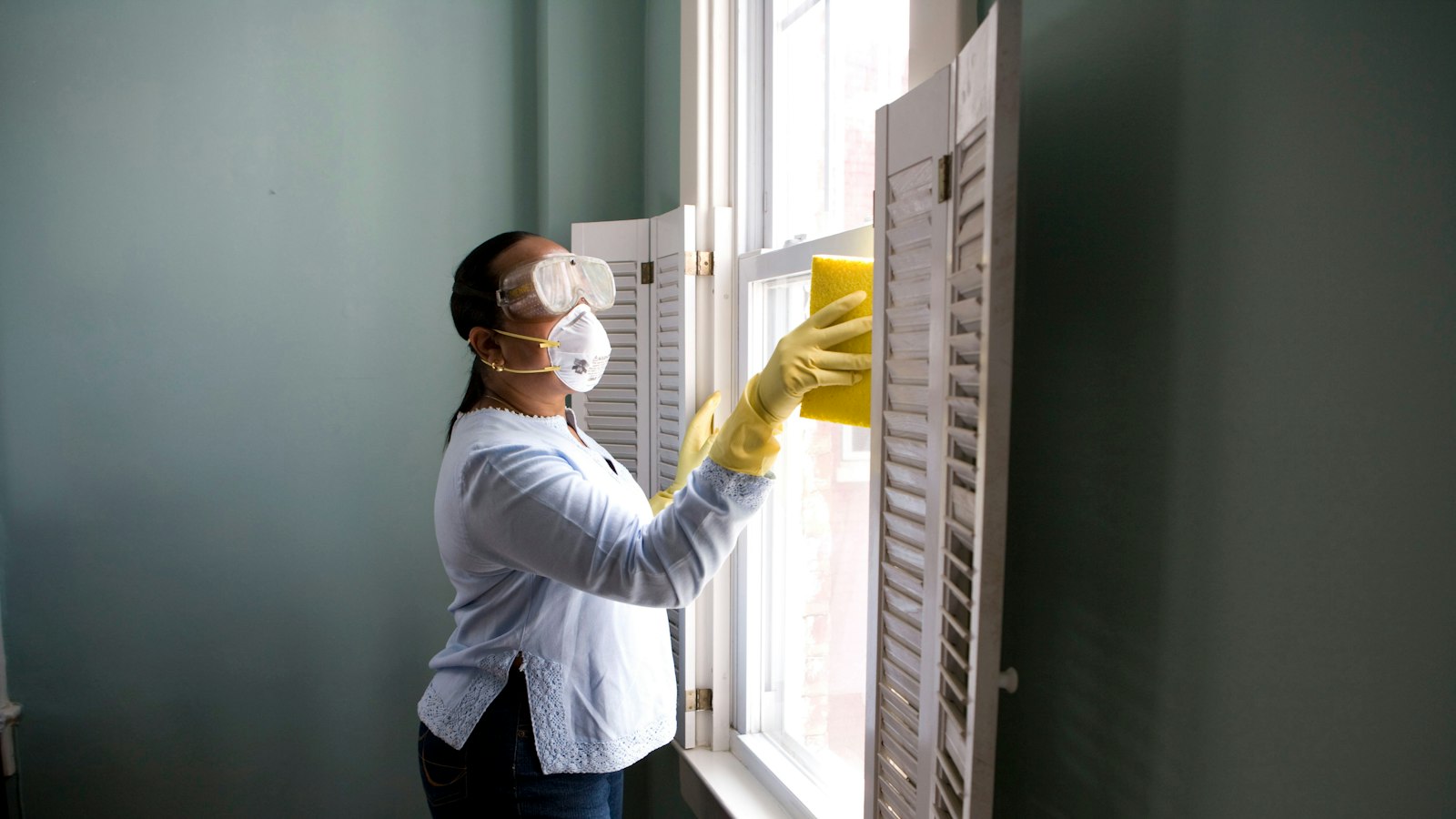 Cleaner in gloves wiping down a window