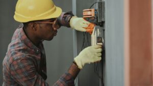 Electrician in a hard hat testing an electrical panel