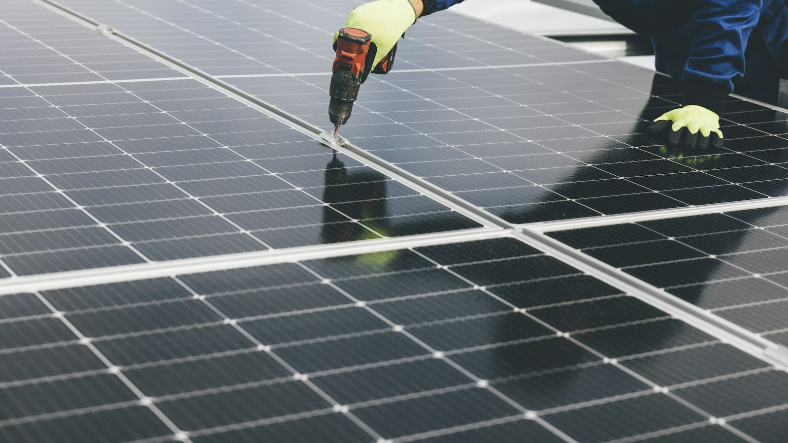 Installer fastening a solar panel on a roof